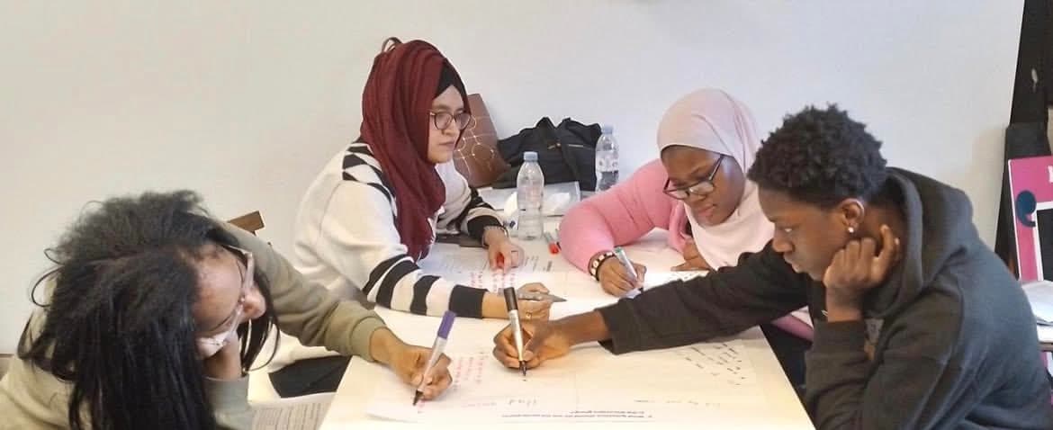 Four people around a table writing notes during a community discussion